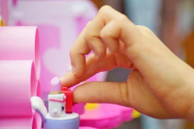 Child's hand playing with miniature toy furniture and accessories.