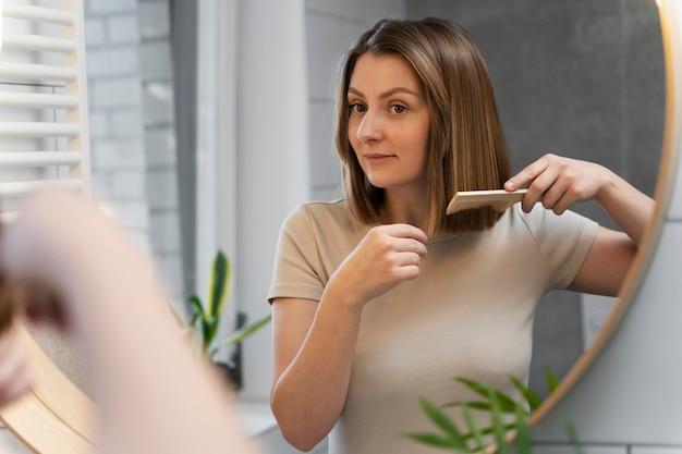 Woman brushing hair in front of mirror