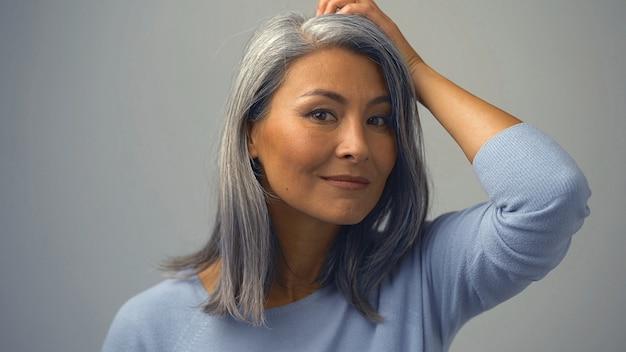 Woman with silver hair smiling in blue sweater