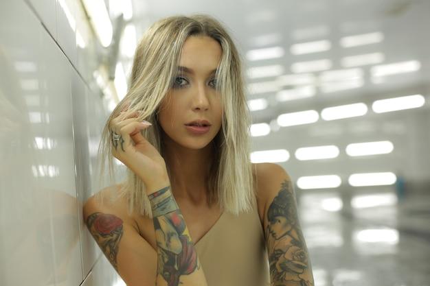 Woman with tattoos posing in a modern hallway